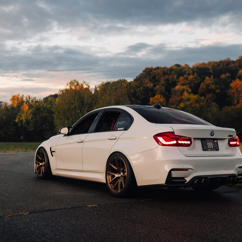 Xe BMW màu trắng độ mâm lồi màu đồng nổi bật giữa trời hoàng hôn